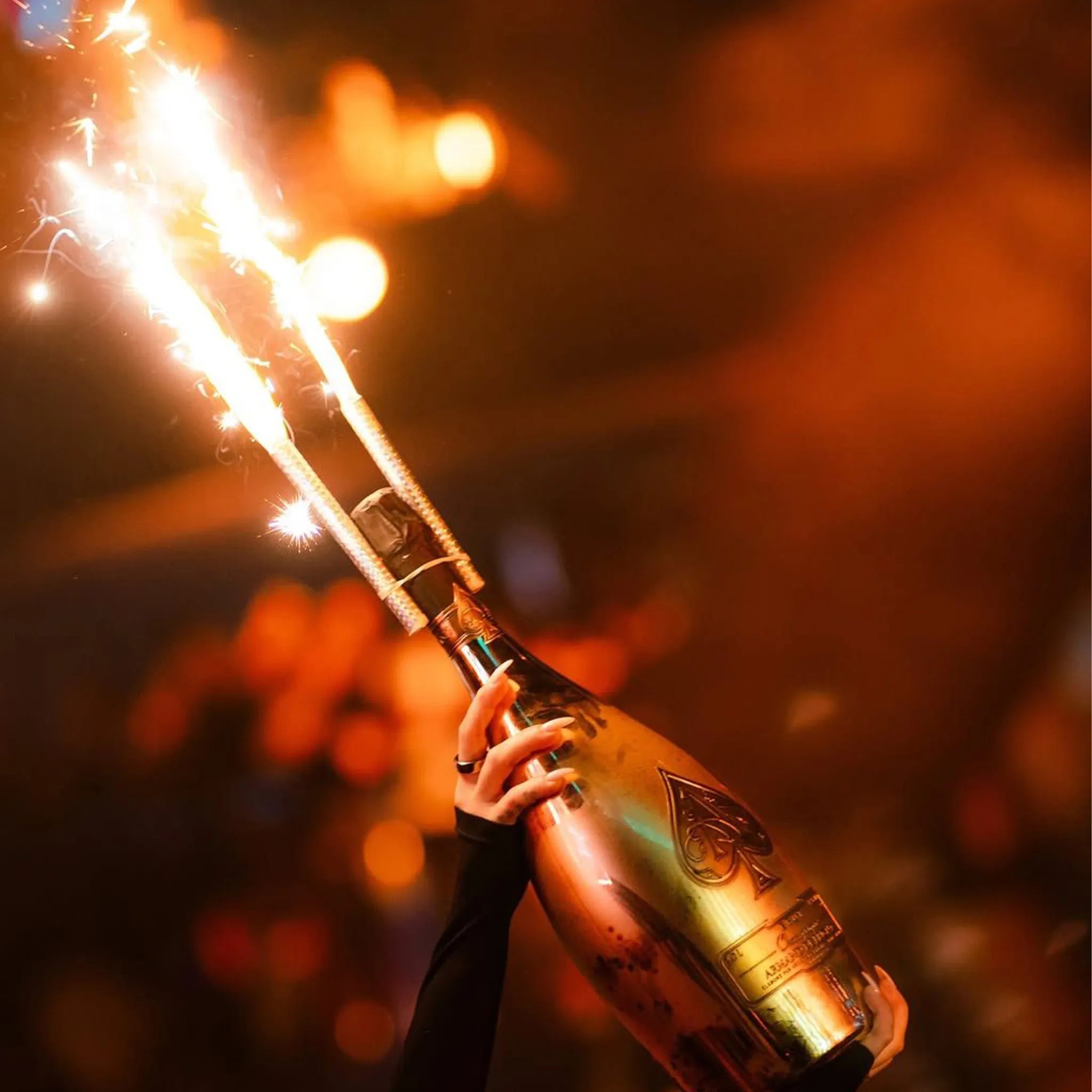 Bottle of champagne with a sparkler against a blurred background